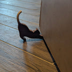 Dog-shaped Koa wood doorstop holding a door open. Functional handmade decor in use on tiled floor