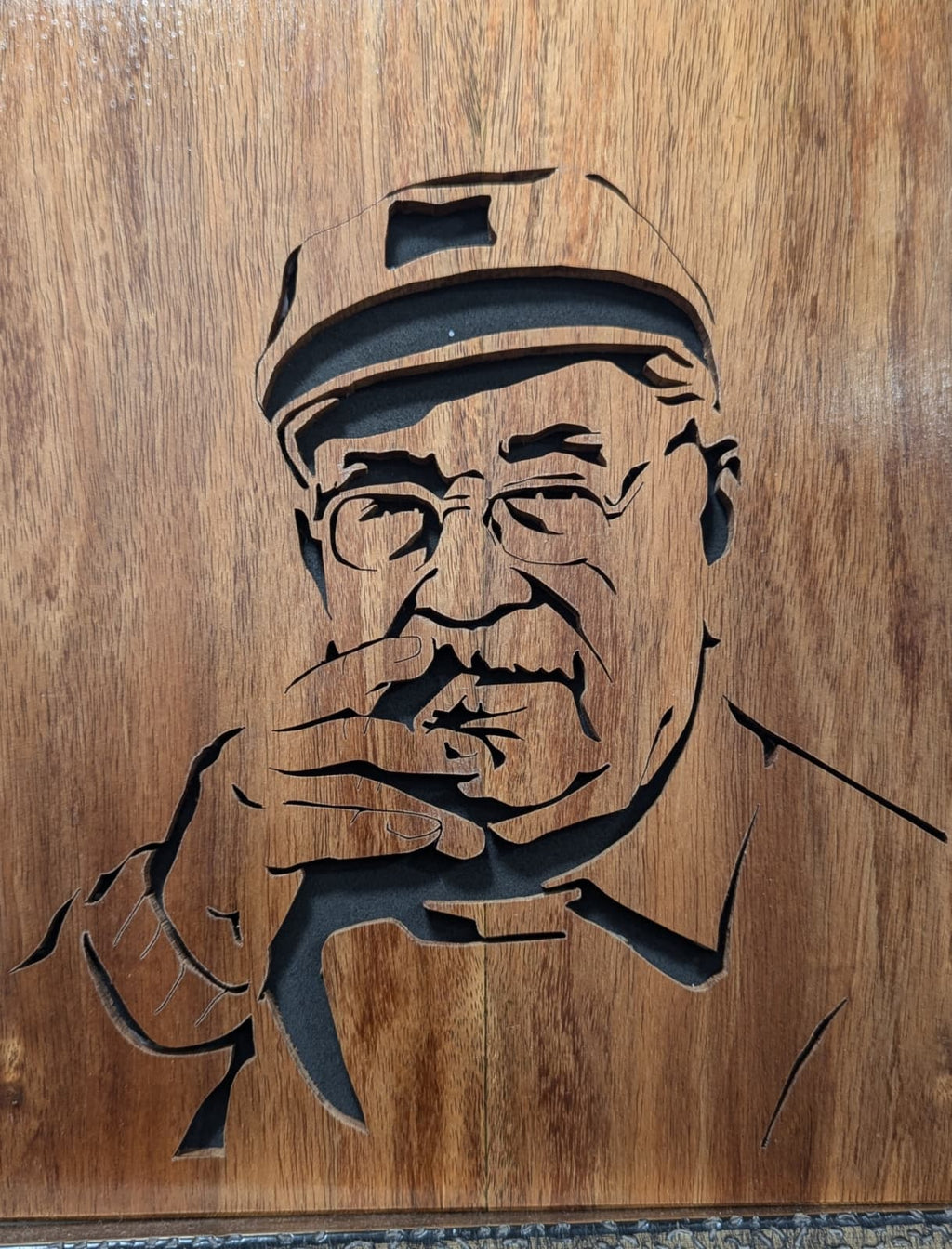 Handcrafted wooden portrait of an elderly man with glasses and cap, custom wood art.