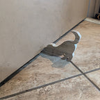 Dog-shaped Koa wood doorstop holding a door open. Functional handmade decor in use on tiled floor